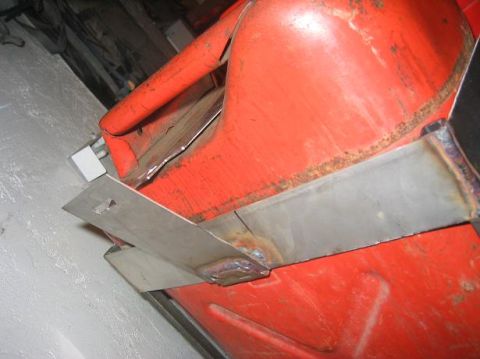 1986 Ford Bronco - A close-up view of a metal bracket welded onto an orange vehicle body panel.