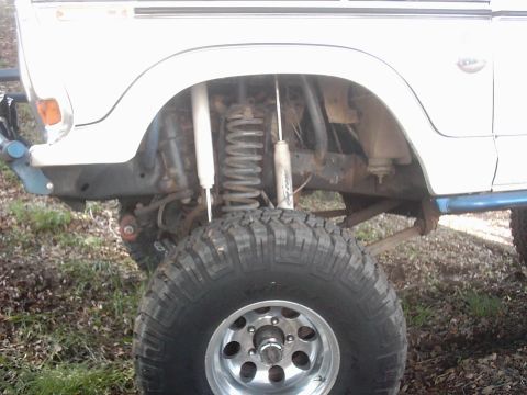 1978 Ford Bronco - Close-up of the front fender and suspension system on a white 1978 Ford Bronco, a large off-road tire.