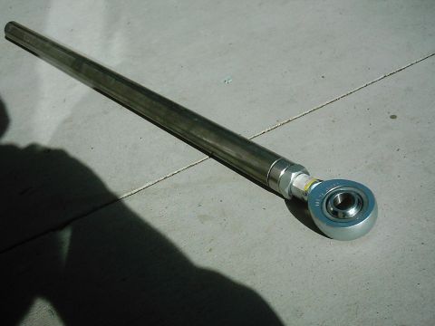 1978 Ford Bronco - A metal rod with a spherical bearing end, likely a suspension component, rests on a concrete surface.