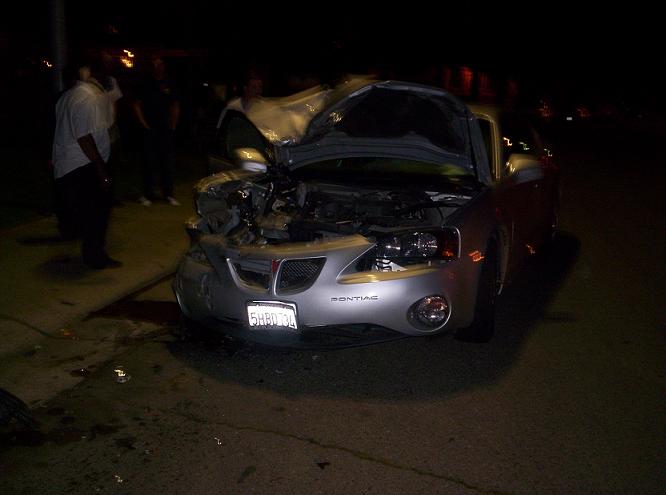 Wrecked silver Pontiac Grand Prix with hood open, front view