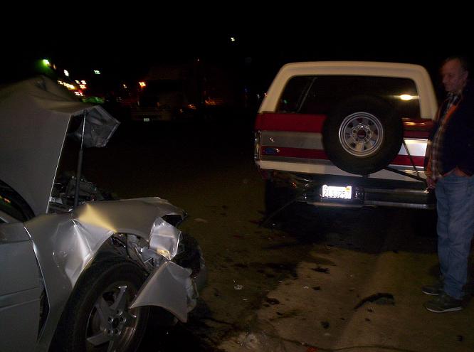 wrecked silver car front end, red and white SUV rear end with spare tire mounted