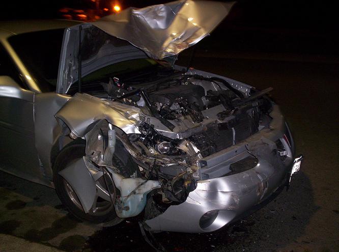 Silver car with severely damaged front end and hood open