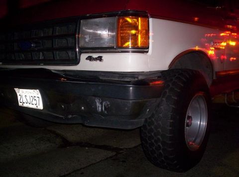 1989 Ford Bronco - Close-up of a white Ford truck's front end, showing the grille, headlight, and a 4x4 badge.