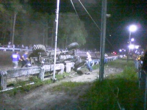 1989 Ford Bronco - An overturned vehicle lies on its side next to a concrete barrier at night, with spectators in the background.