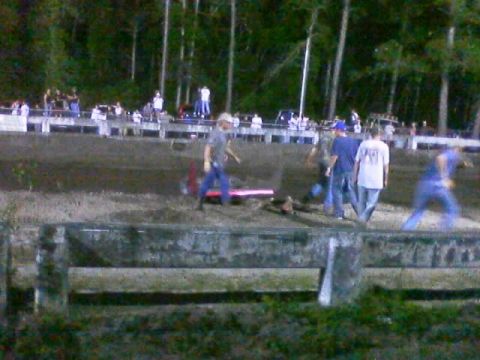 1989 Ford Bronco - Spectators and participants are visible at a dirt track event, with a wooded area behind the stands.