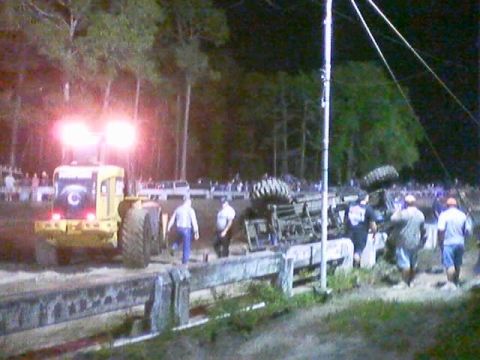 1989 Ford Bronco - Tractor with lights on at a scene with an overturned vehicle and spectators.