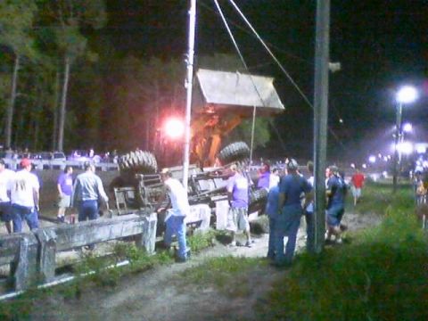 1989 Ford Bronco - An overturned vehicle is surrounded by onlookers at a nighttime event.