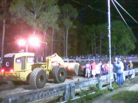 1989 Ford Bronco - A yellow Caterpillar wheel loader is parked on a dirt track at night, illuminated by its bright headlights.