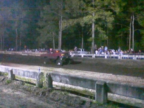 1989 Ford Bronco - Spectators watch a mud bogging event with a red truck in the dirt.