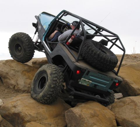 1981 Ford Bronco - Custom off-road vehicle navigating a rocky terrain with a roll cage and large tires.