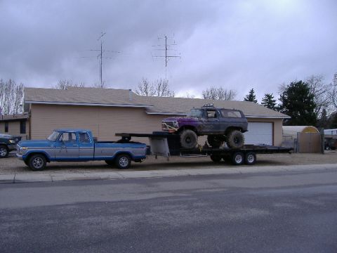 1979 Ford Bronco - A blue Ford pickup truck tows a trailer carrying a lifted purple Bronco.