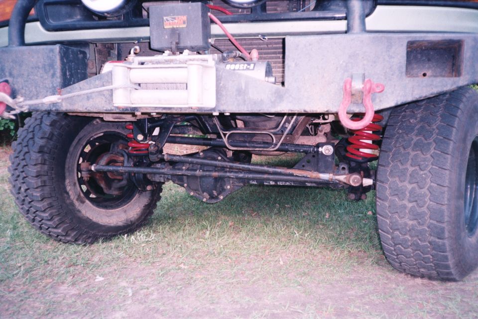 Front axle of lifted Bronco with red coil springs, winch, and D-ring shackle