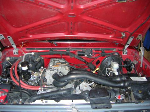 1989 Ford Bronco - The engine bay of a 1989 Ford Bronco, a V8 engine and prominent red hoses.
