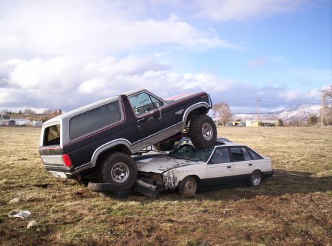 1984 Ford Bronco - A 1984 Ford Bronco is shown crushing a sedan in a junkyard scene.