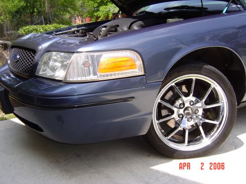 1998 Ford Crown Victoria - A blue Ford Crown Victoria is shown from the front quarter with its hood up and custom wheels.