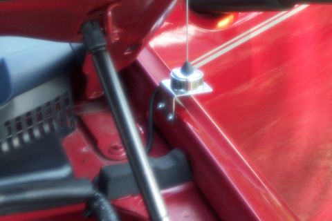 2005 Ford Explorer - Close-up of an antenna mount on a red vehicle's hood, showing part of a gas strut.