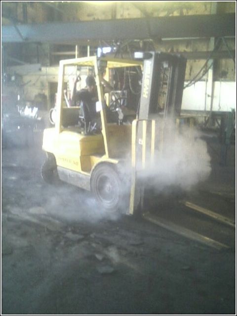 1979 Ford Bronco - A forklift is seen in an industrial setting, releasing a significant amount of smoke.