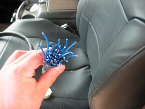 1991 Ford Bronco - A hand holds a bundle of blue wires, likely part of an automotive repair or modification, within the cabin of a vehicle.