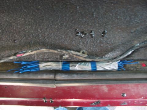 1991 Ford Bronco - Exposed wiring and bundled blue connectors are visible along the door sill of a vehicle.