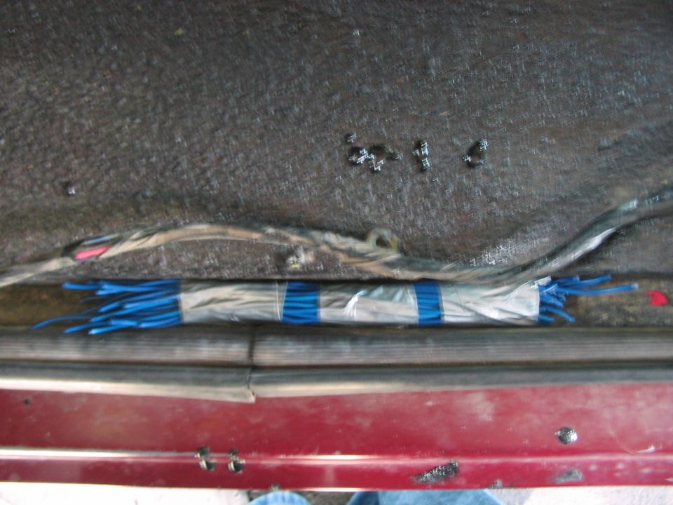 Vehicle door sill with exposed wiring harness and blue wire connectors bundled with tape