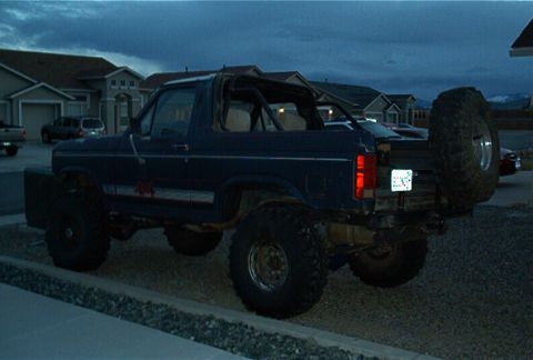 1986 Ford Bronco - Modified 1986 Ford Bronco parked outdoors at dusk with houses in background.