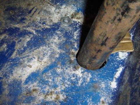 1992 Ford Bronco - Close-up of a rusted pipe on a blue surface with debris and a washer.