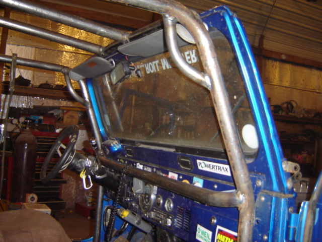 Interior of a blue off-road vehicle with a roll cage, dashboard, and steering wheel visible. Powertrax sticker on dash