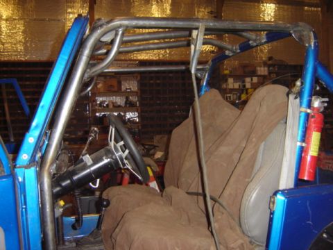 1992 Ford Bronco - Interior view of a blue off-road vehicle, a prominent roll cage and brown seat covers.
