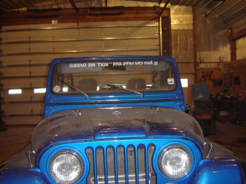 1992 Ford Bronco - A blue Jeep CJ-7 is viewed from the front, showing its distinctive grille and round headlights.