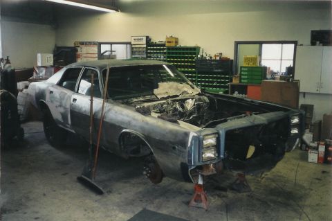 1978 Dodge Monaco - Car body undergoing restoration in a workshop with tools and shelves in the background.