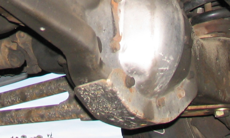 Close-up of a vehicle's differential housing and suspension parts, showing rust and wear