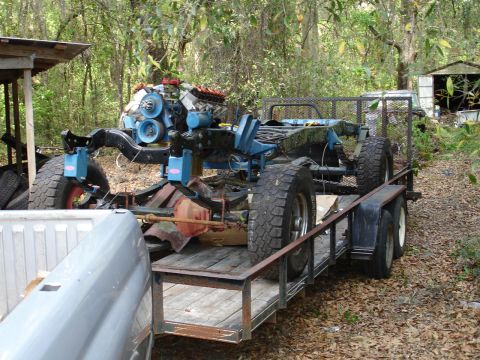 1989 Ford Bronco - A disassembled vehicle chassis with its engine is transported on a trailer.