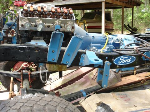 1989 Ford Bronco - The chassis of a Ford truck is shown with its engine and transmission, partially disassembled.