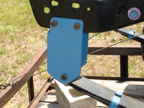 1989 Ford Bronco - A blue bracket is attached to a black frame and leaf spring, possibly for suspension modification.