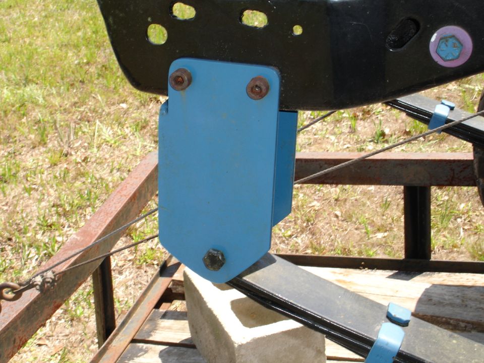 Blue bracket bolted to black frame and leaf spring