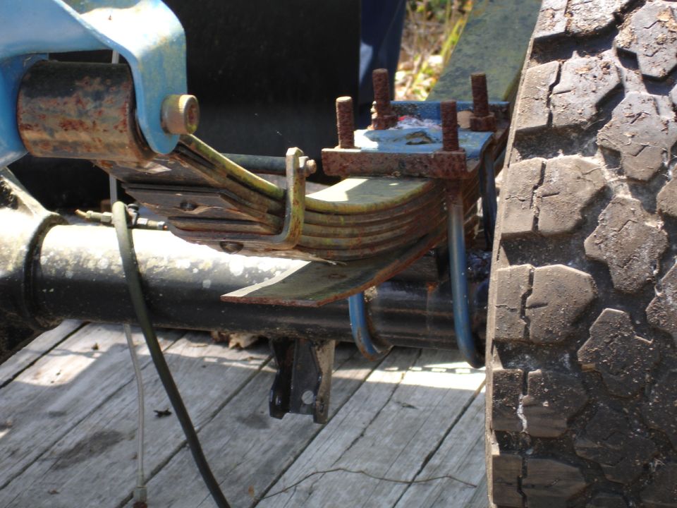 Close-up of a vehicle's leaf spring suspension and tire tread