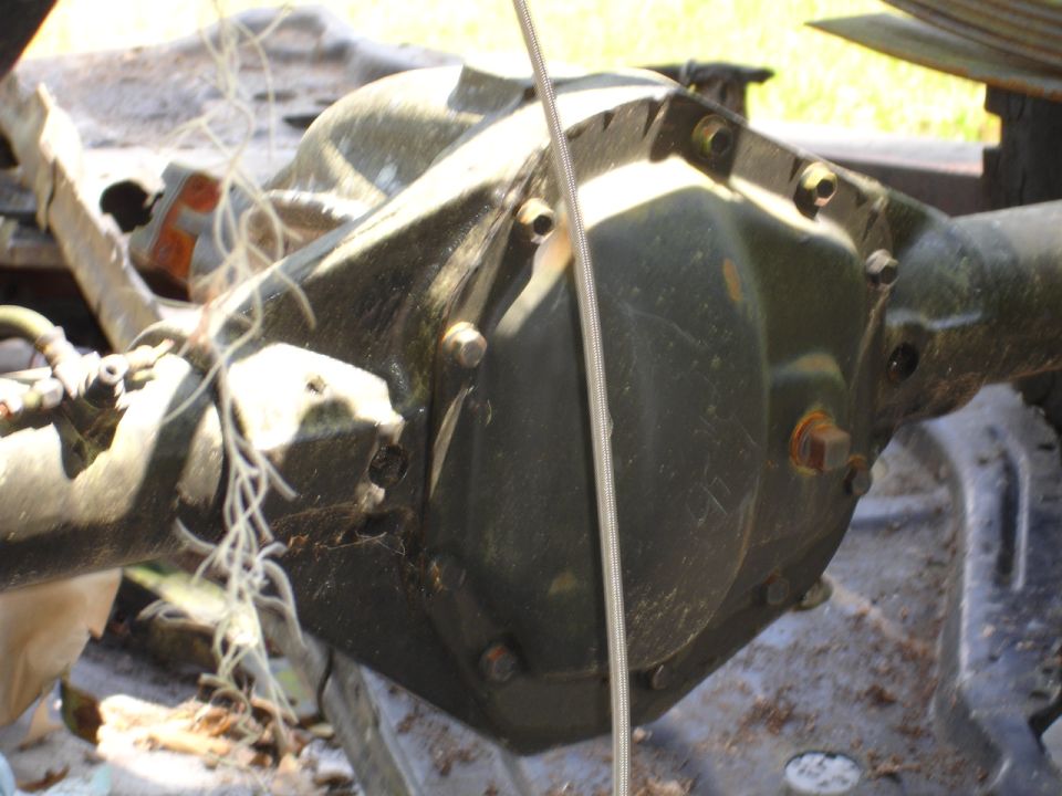 Rear axle differential housing, dark green, with visible bolts and a cable running across
