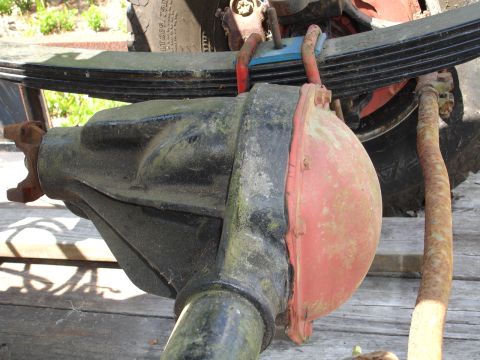 1989 Ford Bronco - Close-up view of a rear axle differential with a red cover, attached to a leaf spring assembly.