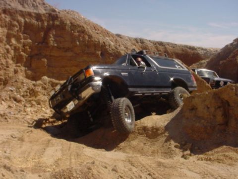 1988 Ford Bronco - A black Ford Bronco navigates a steep, sandy incline with another vehicle visible in the background.