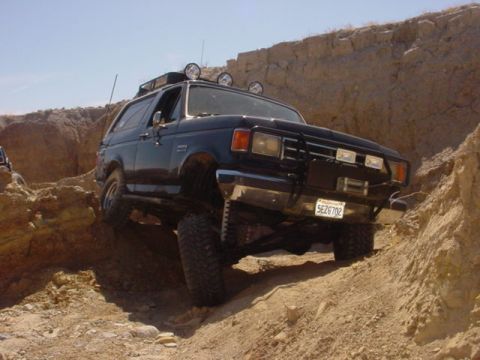 1988 Ford Bronco - Ford Bronco navigating a steep, rocky incline on a sunny day.
