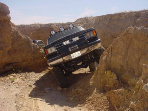 1988 Ford Bronco - A black 1988 Ford Bronco navigates a challenging off-road path, with another vehicle in the background.