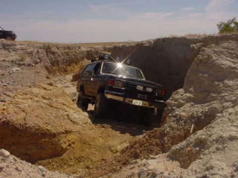 1988 Ford Bronco - A Ford Bronco navigates a narrow dirt path with steep, eroded sides.