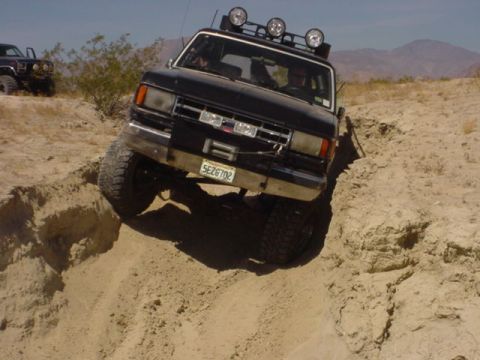 1988 Ford Bronco - This 1988 Ford Bronco is captured in a challenging off-road situation, with another vehicle in the distance.