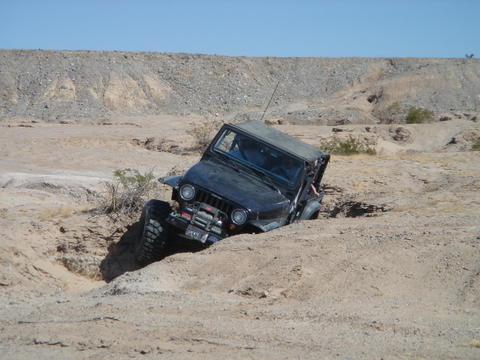 1988 Ford Bronco - Off-road Jeep Wrangler stuck in a deep sandy ditch on a sunny day.