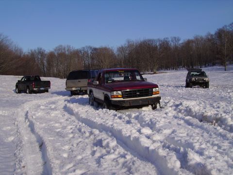 2000 Chevrolet Tahoe - Several vehicles navigate a snowy field under a clear blue sky.