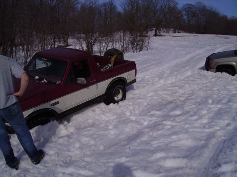 2000 Chevrolet Tahoe - A maroon and white Ford Bronco II is stuck in deep snow, with another vehicle partially visible in the background.