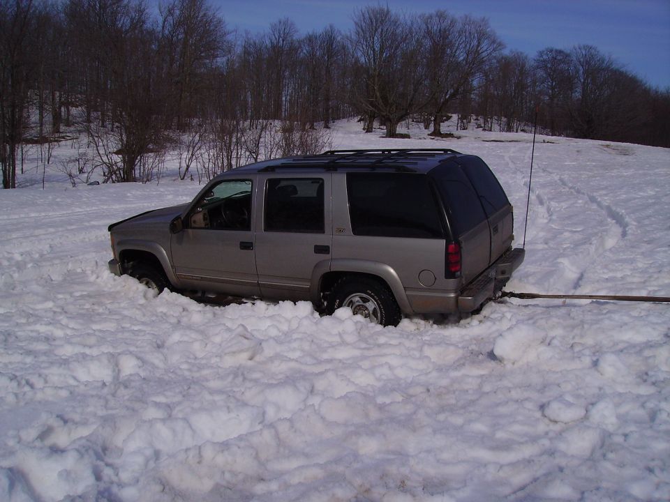 Silver Chevrolet Tahoe stuck deep in snow, front wheel turned left