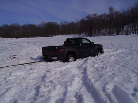 2000 Chevrolet Tahoe - A Chevrolet Colorado pickup truck is stuck in a snowy field, with a tow strap attached to its rear bumper.