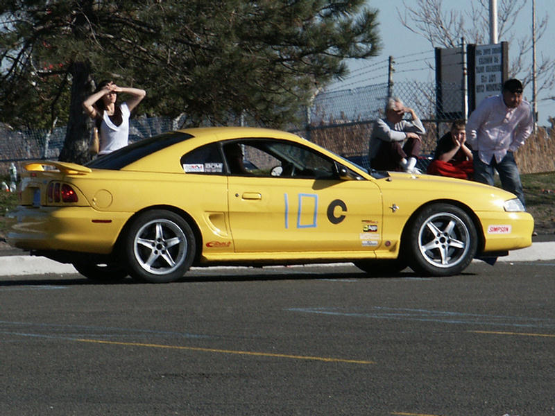 Yellow Ford Mustang with racing numbers 10C on the door and a spoiler