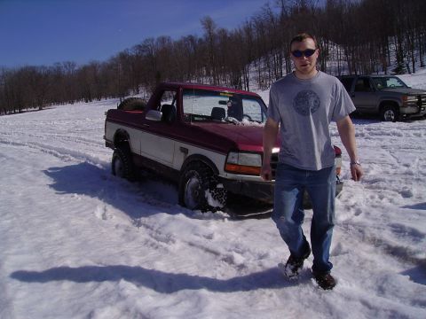 2000 Chevrolet Tahoe - A man walks away from a red and white pickup truck stuck in the snow, with another SUV parked behind it.